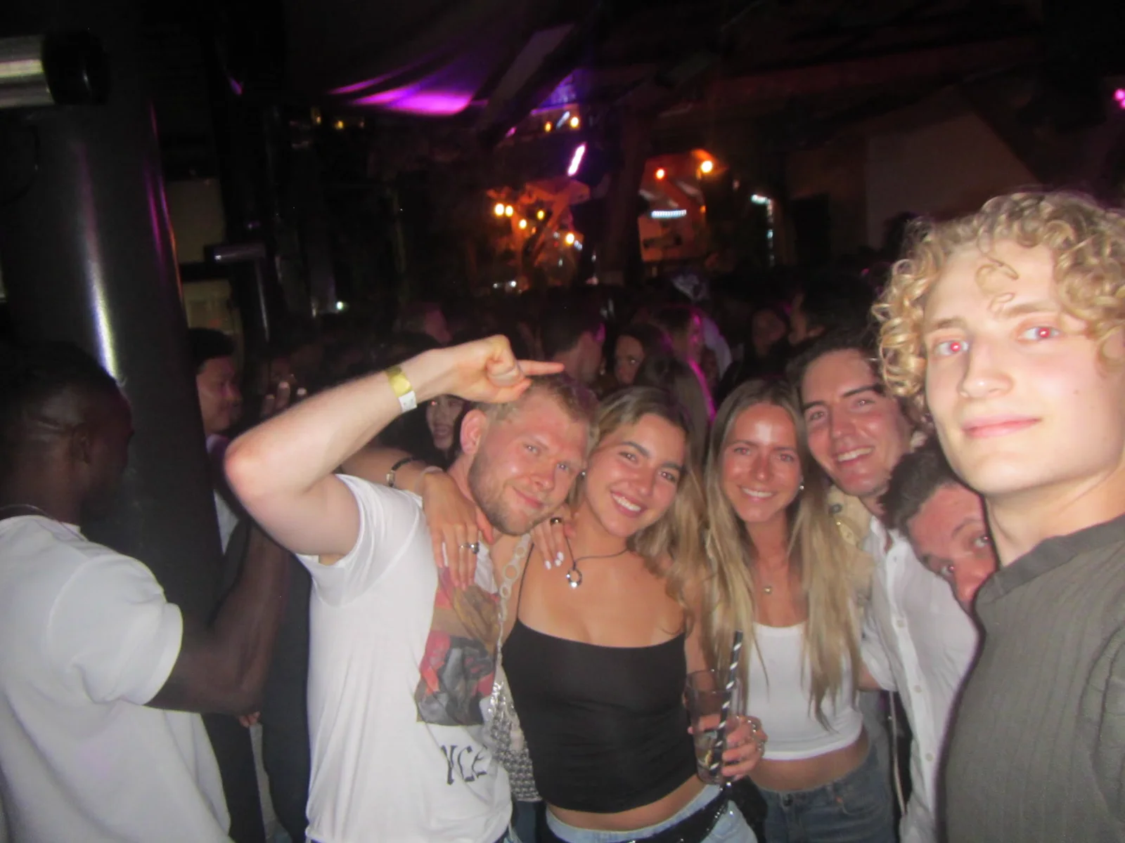 Friends posing together in the middle of a crowded bar