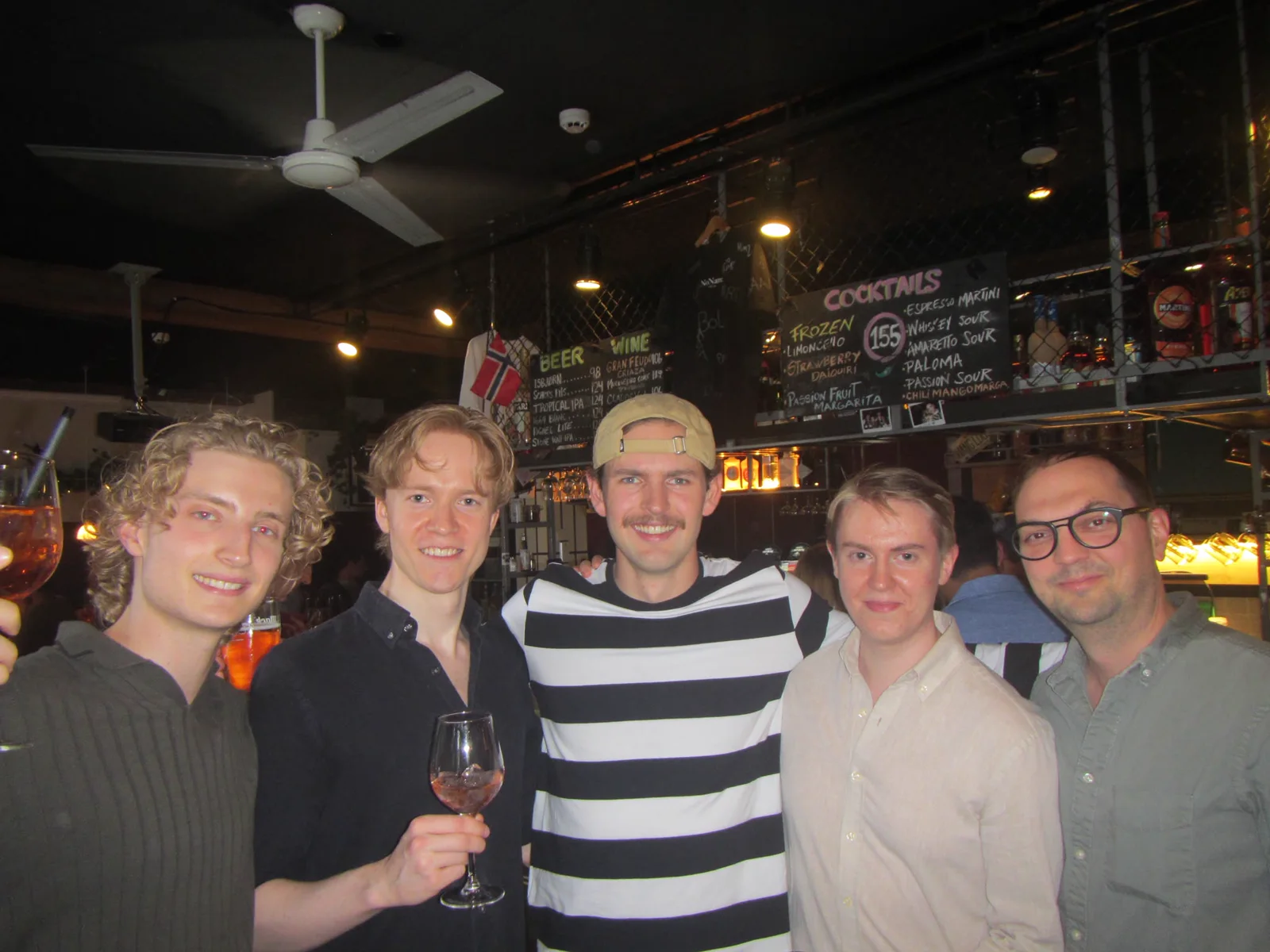 Five friends raising a glass together at the bar